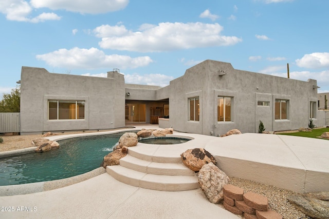 back of property featuring an in ground hot tub, an outdoor pool, a patio, and stucco siding