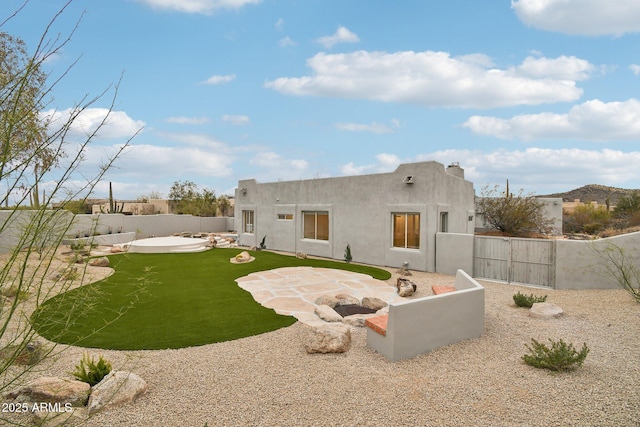 back of house with a gate, a fenced backyard, a patio, and stucco siding