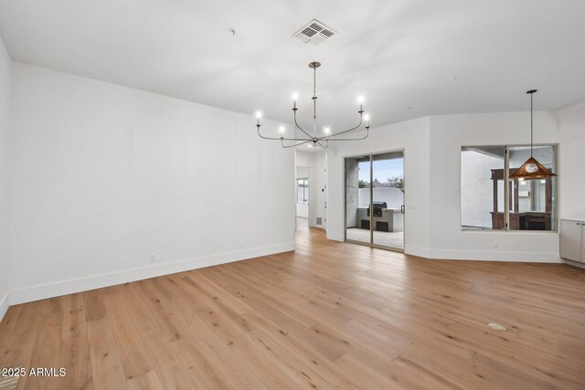 interior space featuring baseboards, light wood-type flooring, visible vents, and a notable chandelier