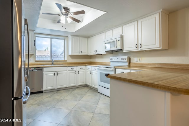 kitchen featuring appliances with stainless steel finishes, sink, a tray ceiling, ceiling fan, and white cabinets