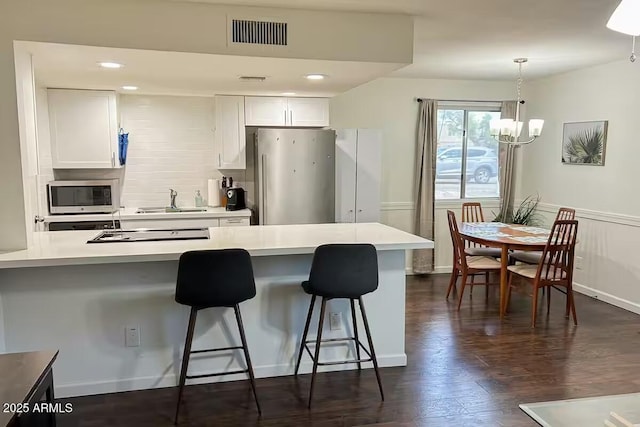 kitchen with pendant lighting, sink, appliances with stainless steel finishes, white cabinets, and a kitchen bar