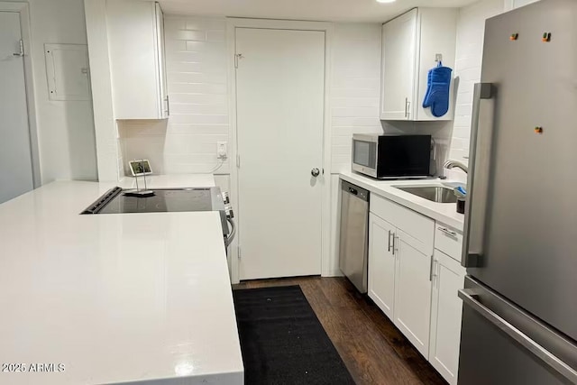 kitchen with appliances with stainless steel finishes, sink, white cabinets, dark hardwood / wood-style flooring, and decorative backsplash