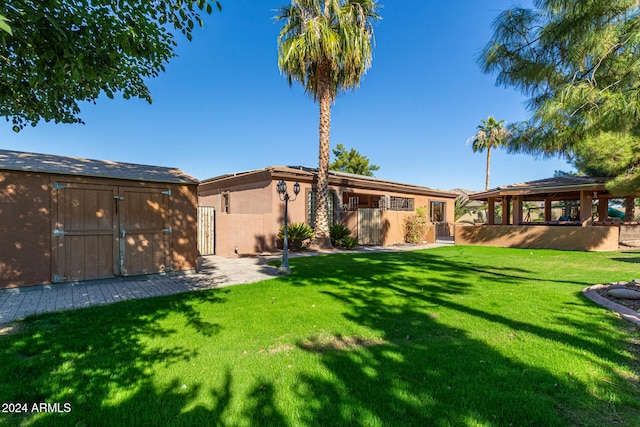 back of property featuring a storage unit and a yard