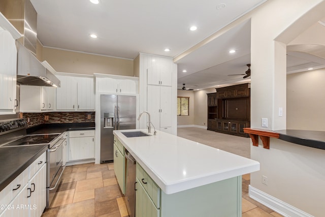 kitchen featuring stainless steel appliances, a kitchen island with sink, ceiling fan, wall chimney range hood, and white cabinets