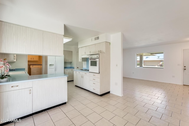 kitchen featuring sink, white appliances, kitchen peninsula, and light tile patterned flooring