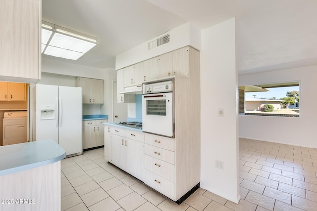 kitchen featuring washer / clothes dryer, white appliances, and light tile patterned flooring