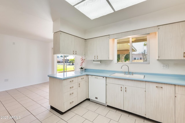 kitchen featuring sink, light tile patterned floors, white dishwasher, and kitchen peninsula