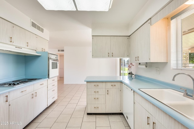 kitchen featuring white appliances, kitchen peninsula, sink, and light tile patterned floors