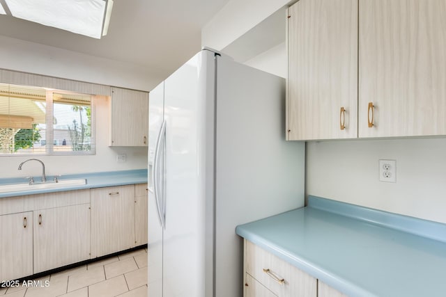 kitchen with sink, light tile patterned floors, and white refrigerator with ice dispenser