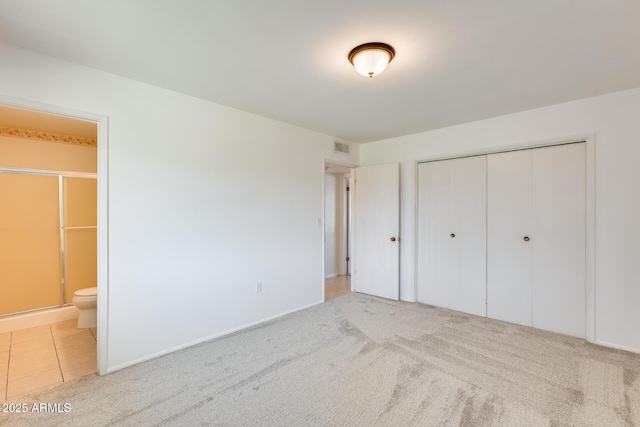 unfurnished bedroom with a closet, connected bathroom, and light carpet