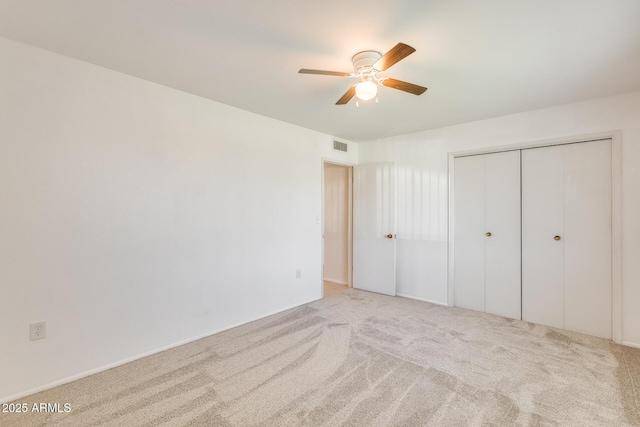 unfurnished bedroom featuring ceiling fan, a closet, and light carpet