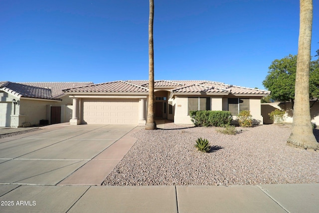 mediterranean / spanish-style house featuring driveway, stucco siding, a tiled roof, and a garage