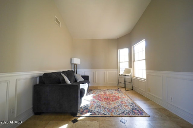 sitting room featuring a decorative wall, visible vents, and wainscoting