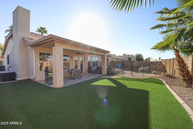 back of house featuring stucco siding, a lawn, a fenced backyard, ceiling fan, and a patio area