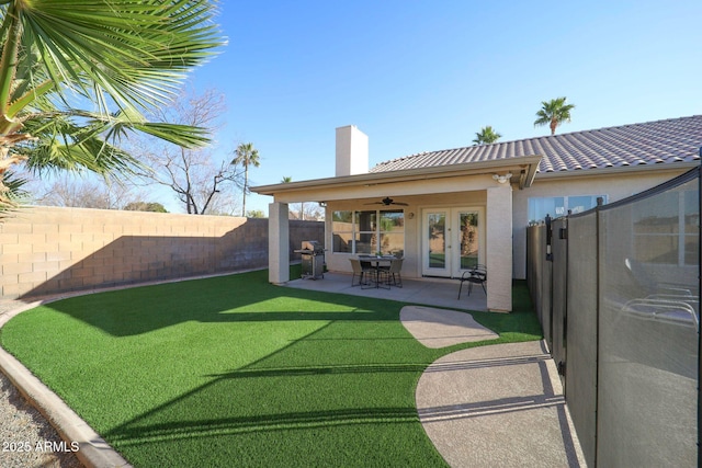 rear view of property featuring french doors, a ceiling fan, a fenced backyard, a chimney, and stucco siding