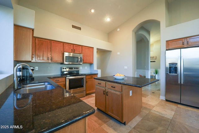 kitchen with visible vents, a sink, high vaulted ceiling, arched walkways, and stainless steel appliances
