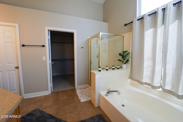 bathroom with a stall shower, baseboards, tile patterned flooring, a garden tub, and a spacious closet