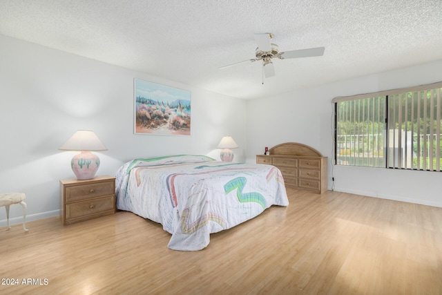 bedroom with ceiling fan, a textured ceiling, and light hardwood / wood-style flooring