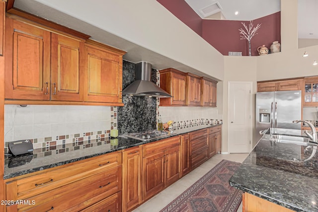 1635 W Windsong Dr, Phoenix, AZ 85045 - kitchen with stainless steel appliances, dark stone counters, a sink, wall chimney range hood, and brown cabinetry