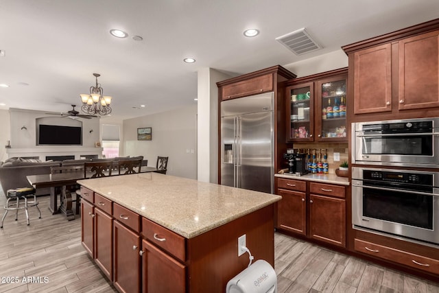 1217 W Fever Tree Ave, San Tan Valley, AZ 85140 - kitchen with appliances with stainless steel finishes, a kitchen island, a chandelier, a ceiling fan, and light wood-type flooring