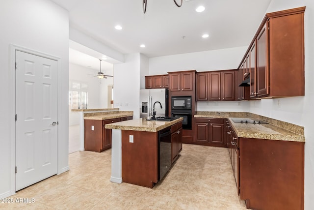 kitchen featuring ceiling fan, a kitchen island with sink, light stone countertops, black appliances, and sink