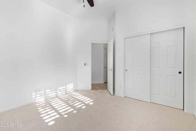 unfurnished bedroom featuring ceiling fan, a closet, and light carpet