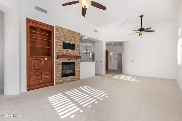 unfurnished living room with ceiling fan with notable chandelier, built in shelves, light carpet, and a fireplace