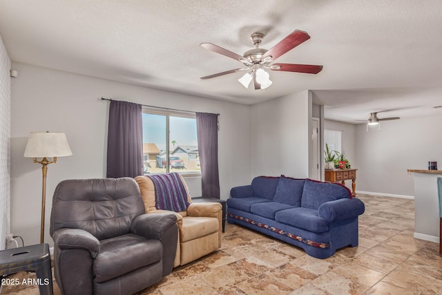 living room featuring ceiling fan and a textured ceiling