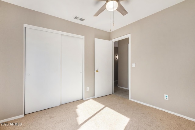 unfurnished bedroom with ceiling fan, light colored carpet, and a closet