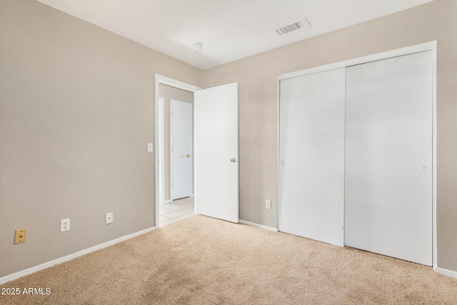 unfurnished bedroom with light colored carpet and a closet