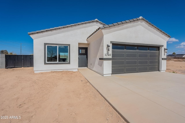 view of front facade featuring a garage, fence, concrete driveway, a tiled roof, and stucco siding