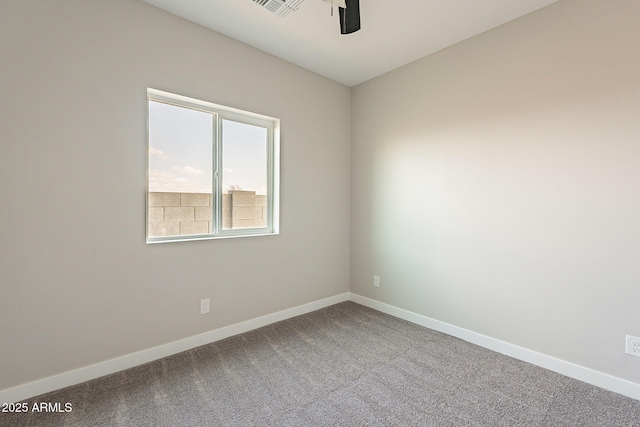 carpeted spare room featuring ceiling fan and baseboards