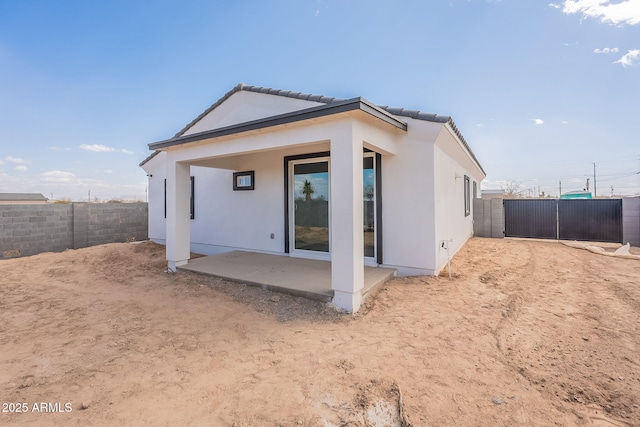 back of house with stucco siding, a fenced backyard, and a patio