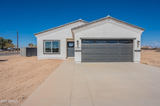 view of front facade with a tile roof, an attached garage, and stucco siding