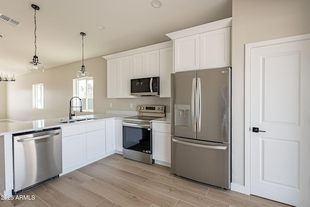 kitchen featuring stainless steel appliances, wood finish floors, visible vents, and a sink