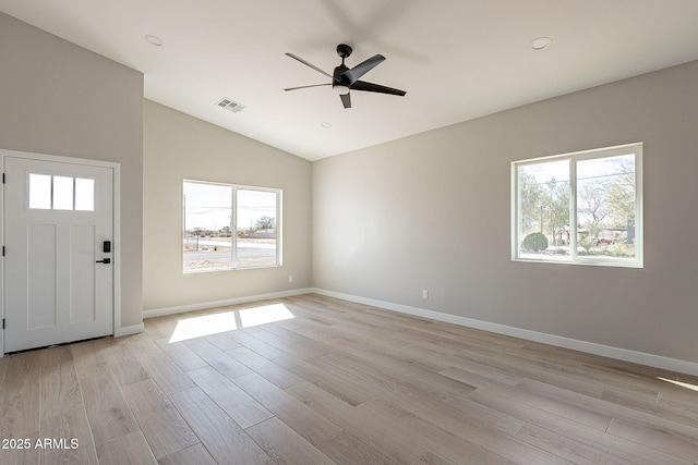 interior space featuring vaulted ceiling, light wood-type flooring, visible vents, and baseboards