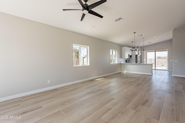 unfurnished living room with lofted ceiling, visible vents, baseboards, a ceiling fan, and light wood finished floors