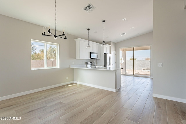 kitchen with light countertops, visible vents, light wood-style flooring, appliances with stainless steel finishes, and a peninsula