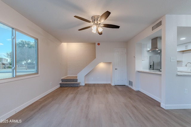 unfurnished living room featuring ceiling fan and light hardwood / wood-style floors