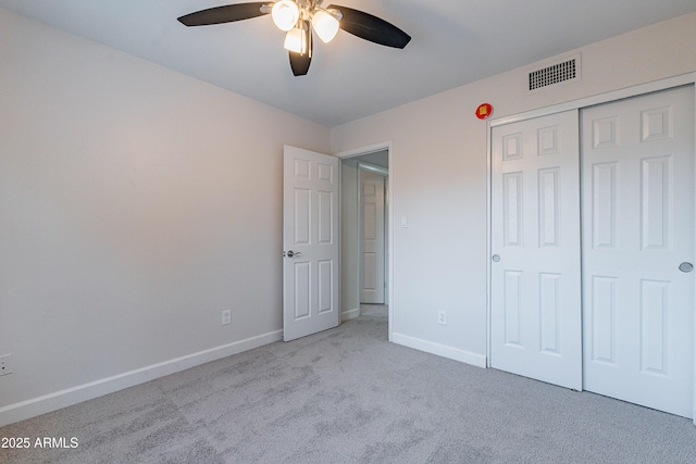 unfurnished bedroom with light colored carpet, a closet, and ceiling fan