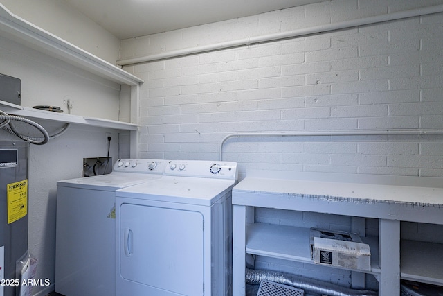 laundry room featuring separate washer and dryer, water heater, and brick wall