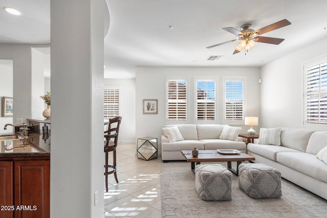 living room featuring a healthy amount of sunlight, sink, light tile patterned floors, and ceiling fan