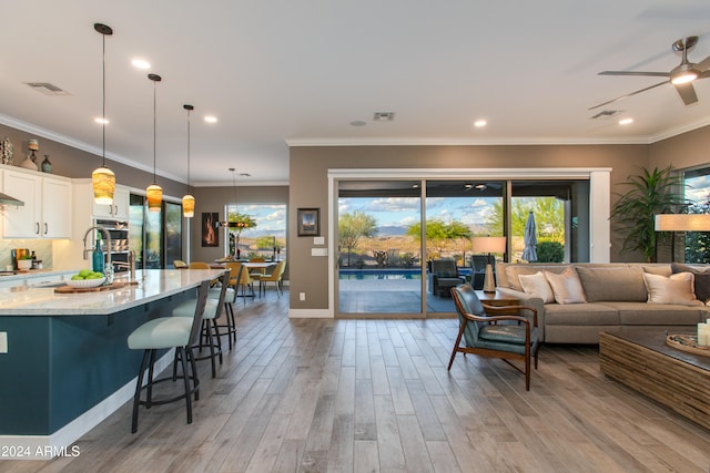 living room with crown molding, light hardwood / wood-style flooring, and ceiling fan