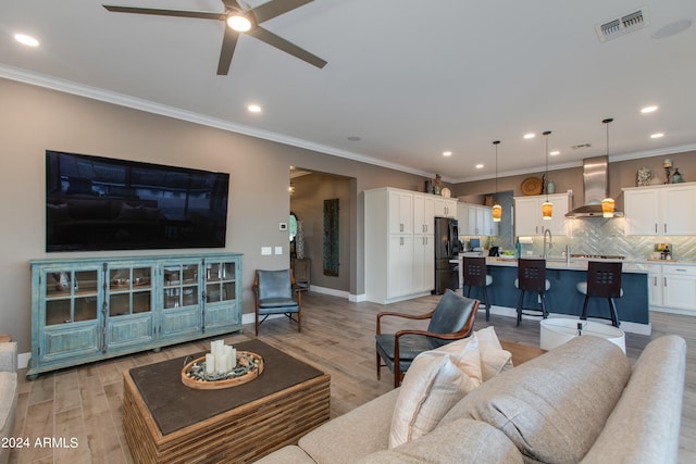 living room with light hardwood / wood-style flooring, ornamental molding, and ceiling fan