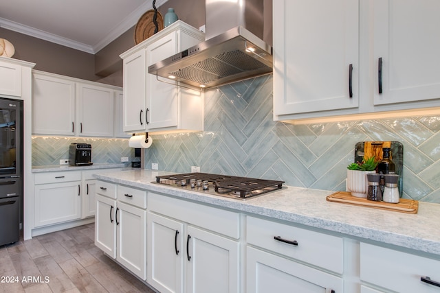 kitchen with wall chimney exhaust hood, ornamental molding, white cabinets, and tasteful backsplash