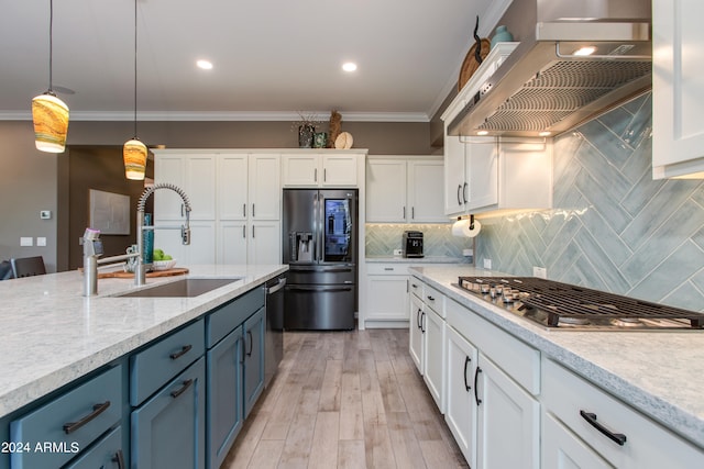 kitchen with sink, blue cabinets, hanging light fixtures, stainless steel appliances, and wall chimney exhaust hood