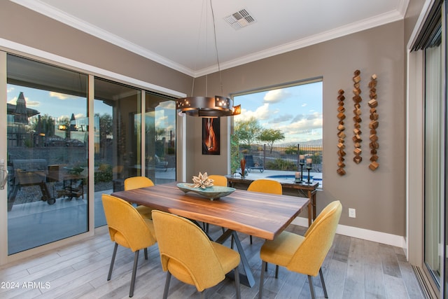 dining room with an inviting chandelier, ornamental molding, and light wood-type flooring