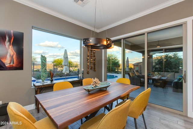 dining area with crown molding, a notable chandelier, light hardwood / wood-style flooring, and plenty of natural light