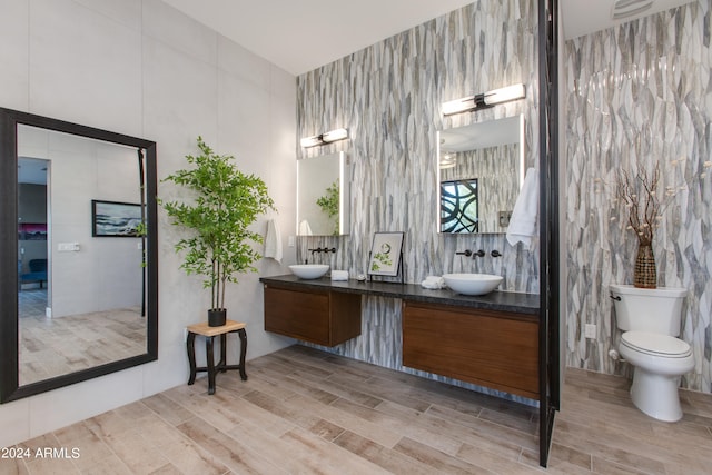 bathroom featuring vanity, hardwood / wood-style flooring, toilet, and tile walls