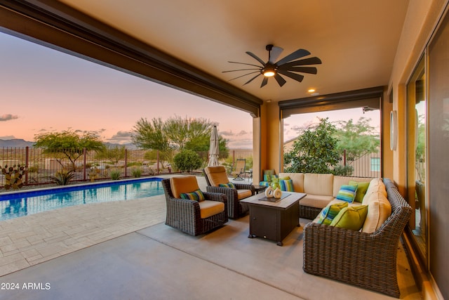 patio terrace at dusk with an outdoor hangout area, a fenced in pool, and ceiling fan